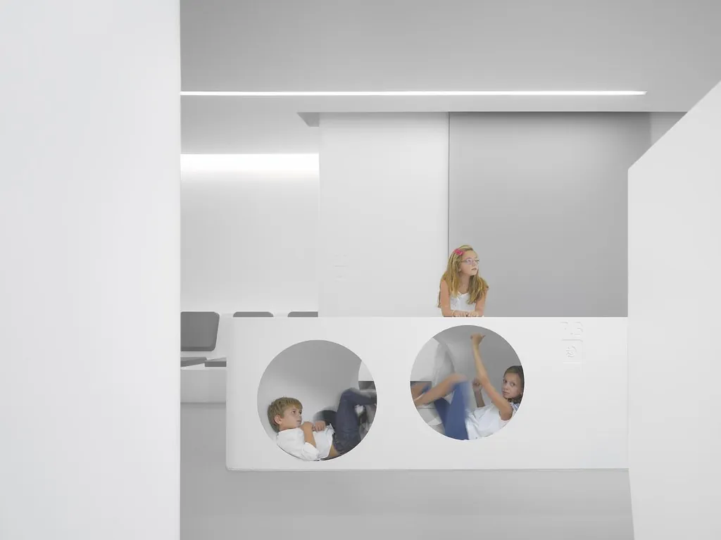 Recepción blanca y luminosa con dos ventanas circulares